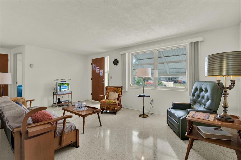 A living room with terrazzo floors, a wooden front door, and several pieces of furniture — 1617 DERRICK STREET, HOLIDAY, FL