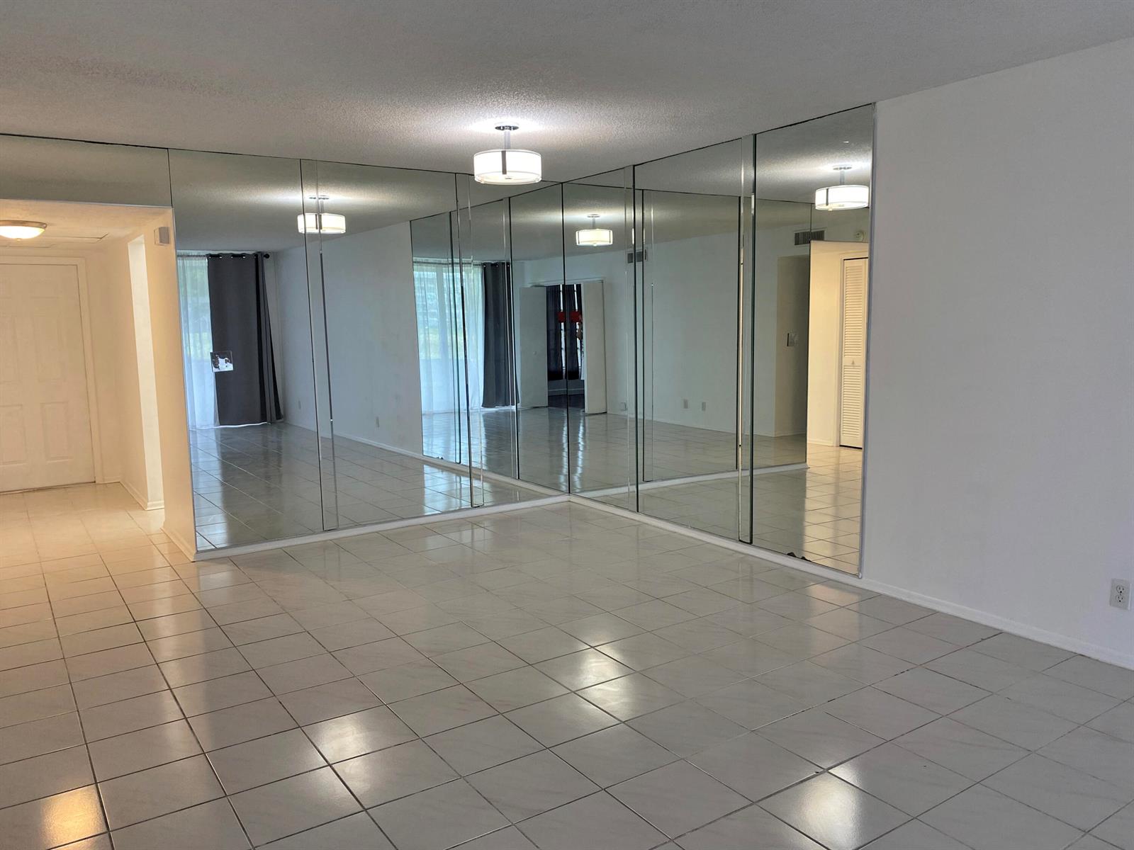 A room with white tiled floors and a large wall covered in floor-to-ceiling mirrors — 2751 S Palm Aire Drive # 107, Pompano Beach FL 33069, POMPANO BEACH, FL