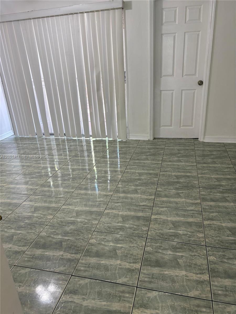 A room with light green marble-patterned tile flooring, vertical blinds, and a white door — 270 NE 142nd St # 14A, Miami FL 33161, MIAMI, FL