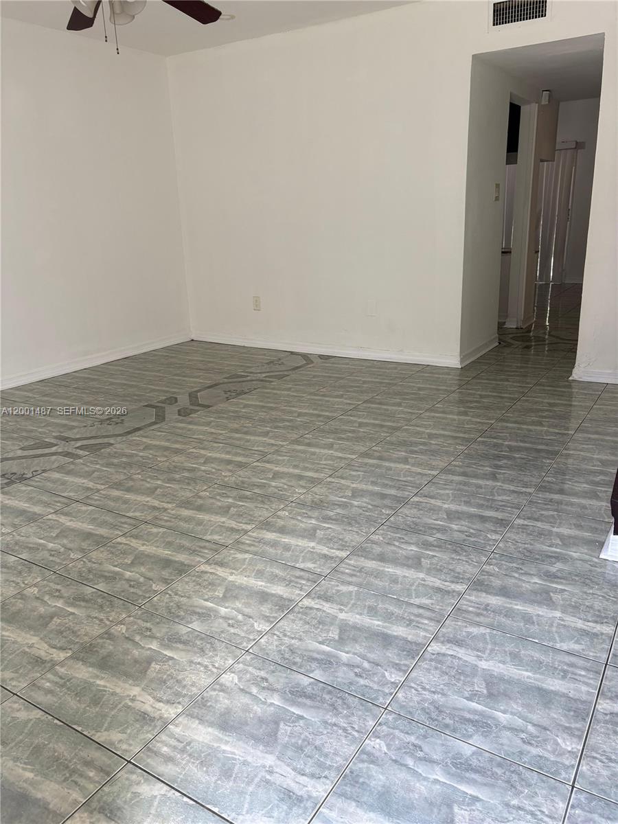 A room with white walls and gray marble-patterned tile flooring features a ceiling fan — 270 NE 142nd St # 14A, Miami FL 33161, MIAMI, FL