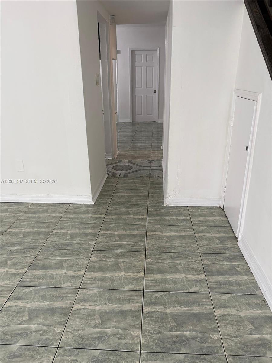 A hallway with gray marble-patterned tile flooring leads toward a closed white door — 270 NE 142nd St # 14A, Miami FL 33161, MIAMI, FL