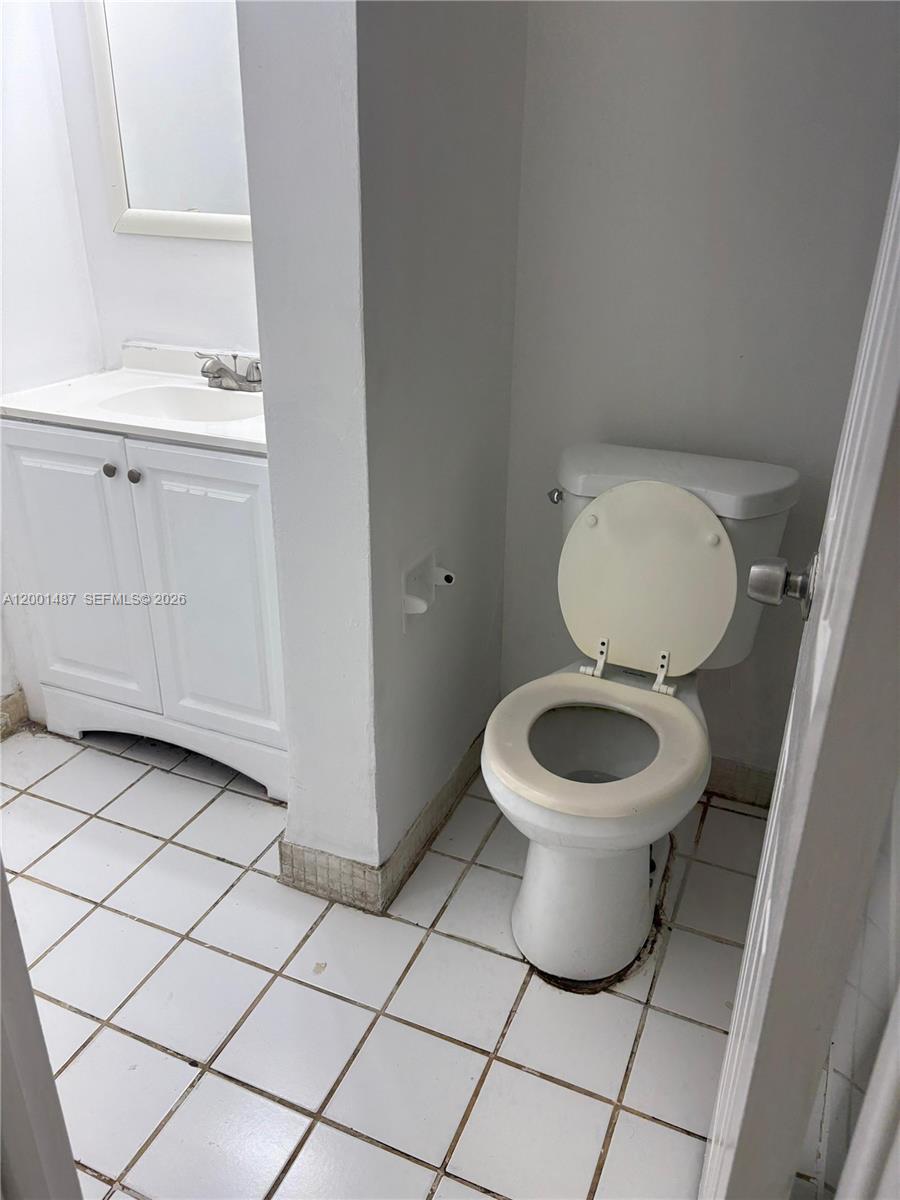 A small bathroom features a white vanity, a toilet, and white tiled flooring — 270 NE 142nd St # 14A, Miami FL 33161, MIAMI, FL