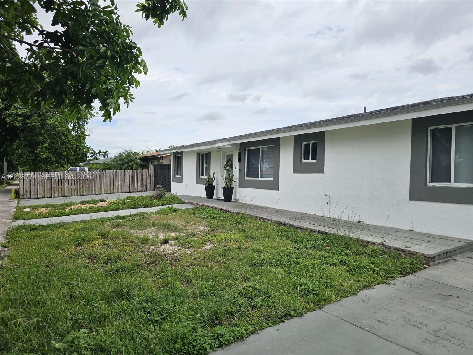 A single-story white house with gray trim features a front walkway and a grassy yard — 75 SW 18th Ave, Homestead FL 33030, HOMESTEAD, FL