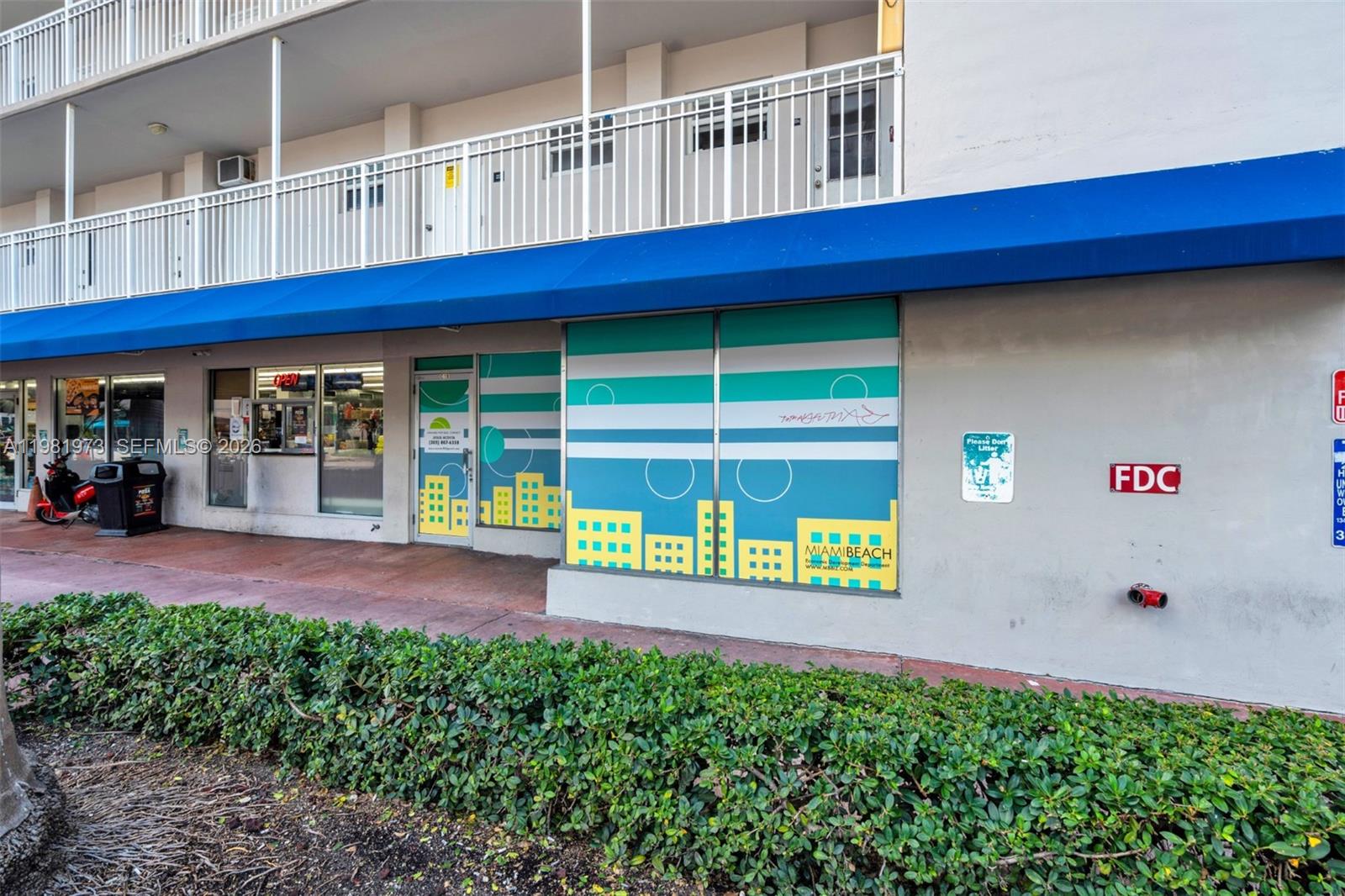 The exterior of a commercial building features a blue awning, storefront windows, and decorative graphics — 1300 Lincoln Rd # 1B, Miami Beach FL 33139, MIAMI BEACH, FL