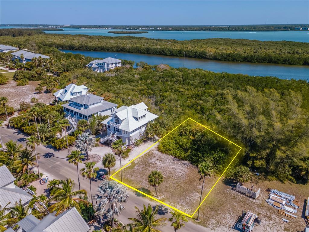 An aerial view shows a vacant residential lot outlined in yellow next to coastal houses — 7395 PALM ISLAND DRIVE Lot 22, PLACIDA, FL