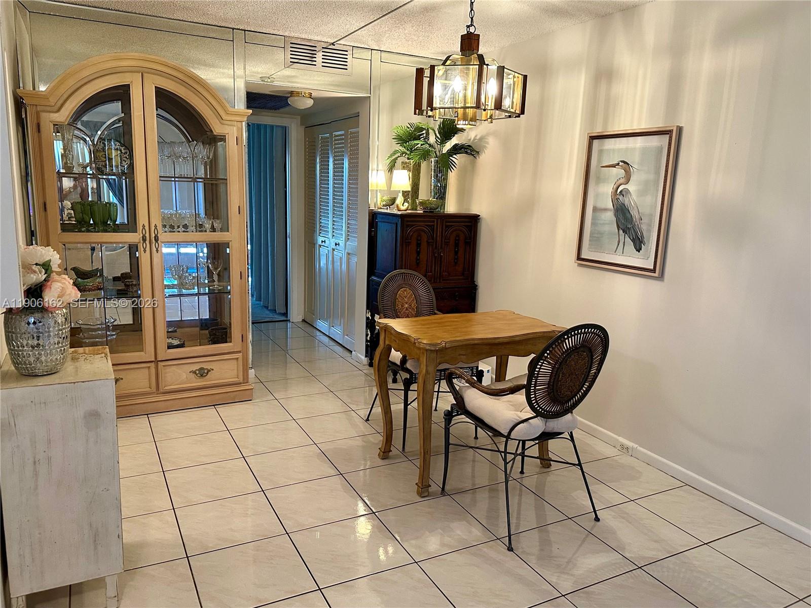 A dining area features a wooden table, two chairs, a china cabinet, and tiled floors — 142 Preston D # 142, Boca Raton FL 33434, BOCA RATON, FL