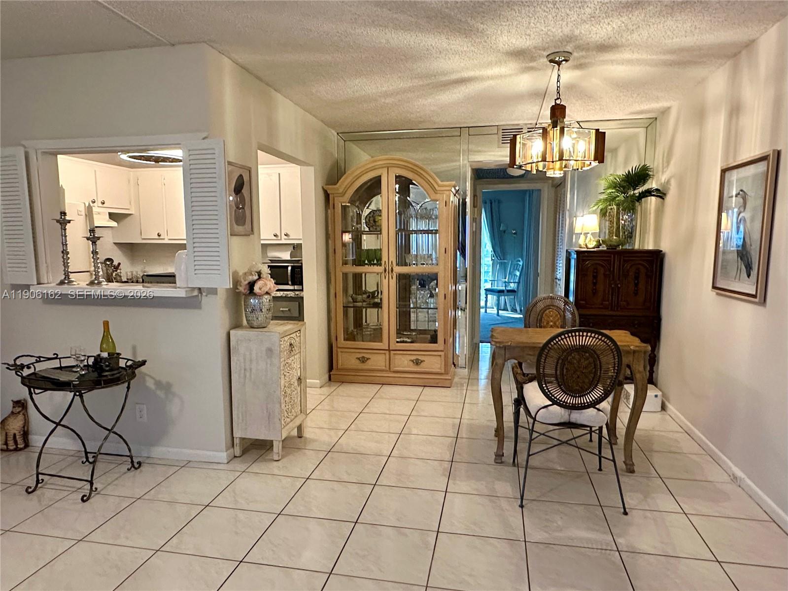 A dining area with tile flooring, a glass-front cabinet, and a view into the kitchen — 142 Preston D # 142, Boca Raton FL 33434, BOCA RATON, FL