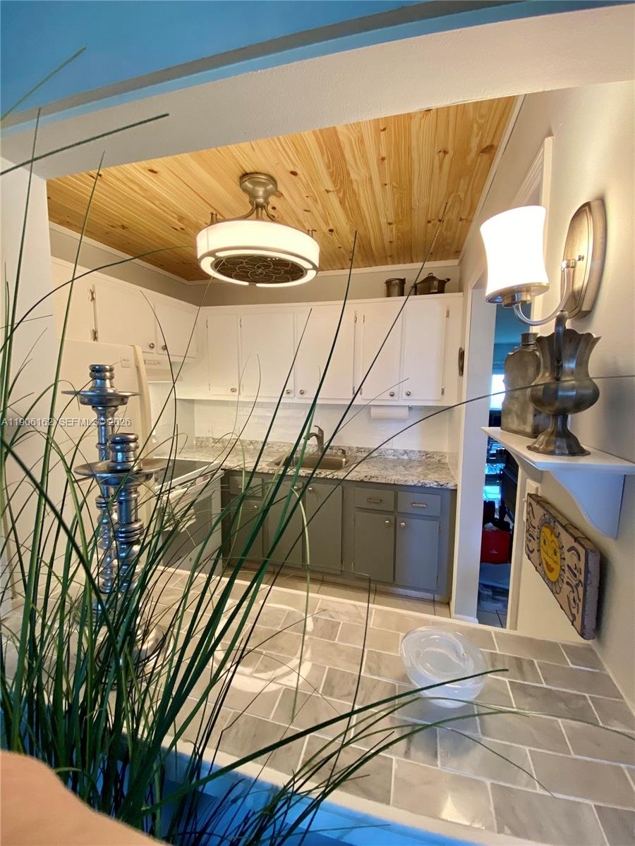 A kitchen features white upper cabinets, grey lower cabinets, and a wood-paneled ceiling — 142 Preston D # 142, Boca Raton FL 33434, BOCA RATON, FL