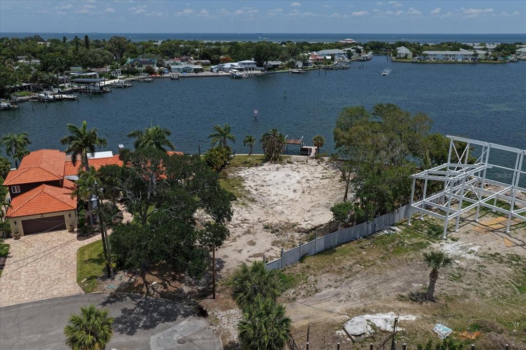 An aerial view shows a vacant waterfront lot next to a house with a tile roof — 4838 PARADISE WAY S, ST PETERSBURG, FL