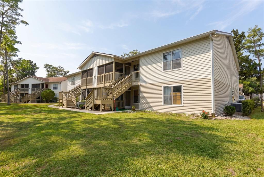 Exterior view of a two-story apartment building with tan siding and wooden staircases — 1600 BIG TREE ROAD UNIT G3, SOUTH DAYTONA, FL