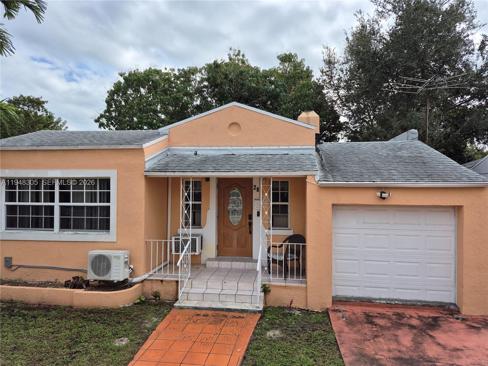 A single-story peach-colored house features a front porch, a garage, and a tiled walkway — 28 NE 49th St # 0, Miami FL 33137, MIAMI, FL