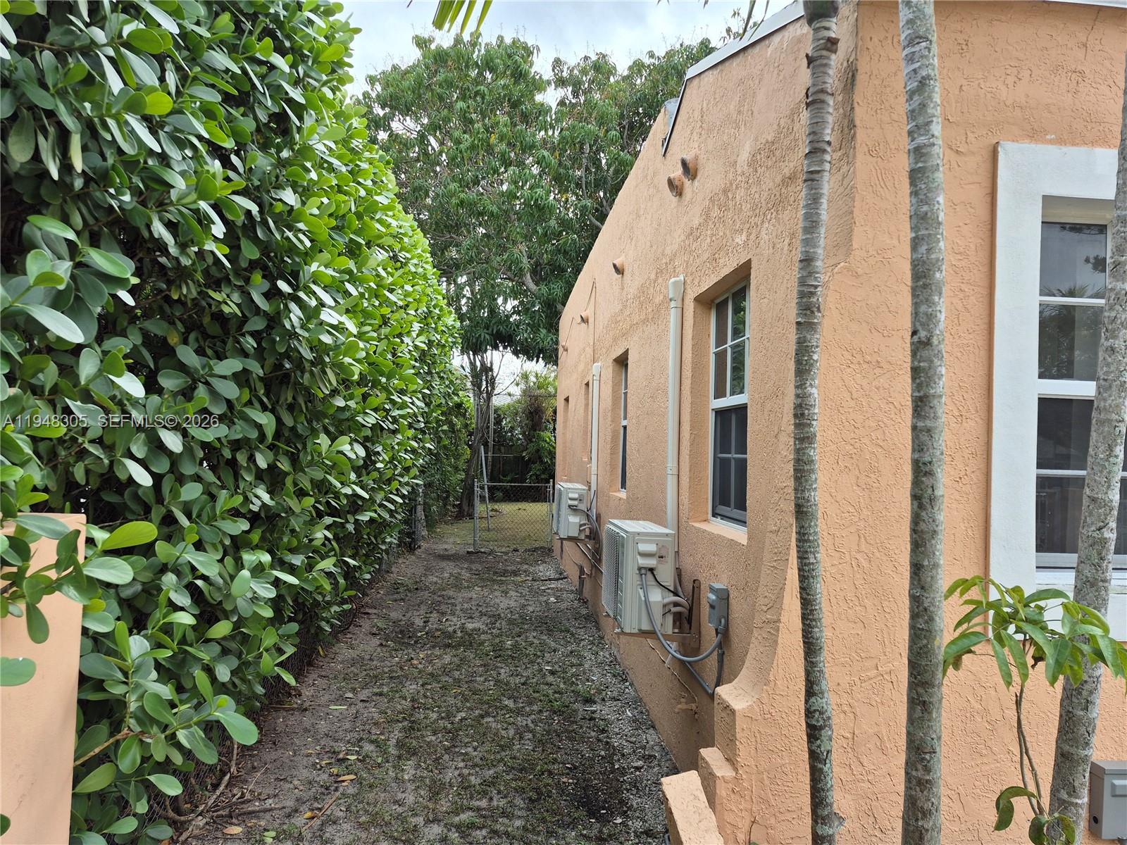 A side yard features a peach-colored stucco wall with two air conditioning units and windows — 28 NE 49th St # 0, Miami FL 33137, MIAMI, FL
