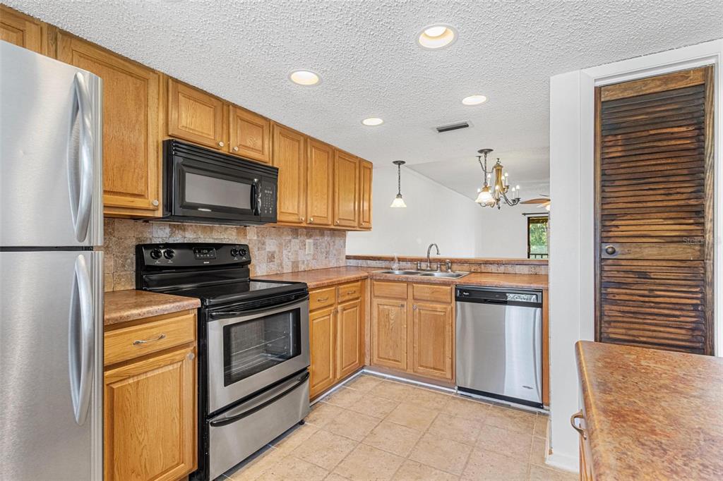A kitchen with oak cabinets, stainless steel appliances, and a tiled backsplash — 108 WOODLANDS COURT UNIT 108, OLDSMAR, FL