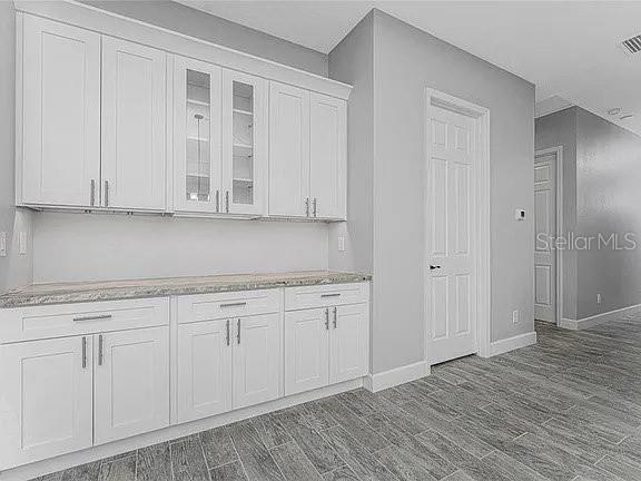 A kitchen or butler's pantry features white cabinets, granite countertops, and gray tile flooring — 1038 SAN CRISTOBAL AVENUE, PUNTA GORDA, FL