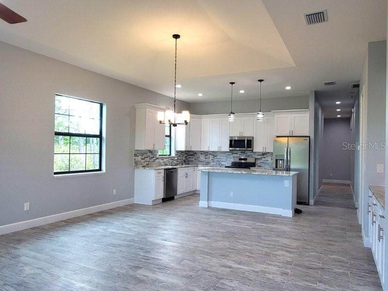 A kitchen with white cabinets, stainless steel appliances, and a light blue island — 1038 SAN CRISTOBAL AVENUE, PUNTA GORDA, FL