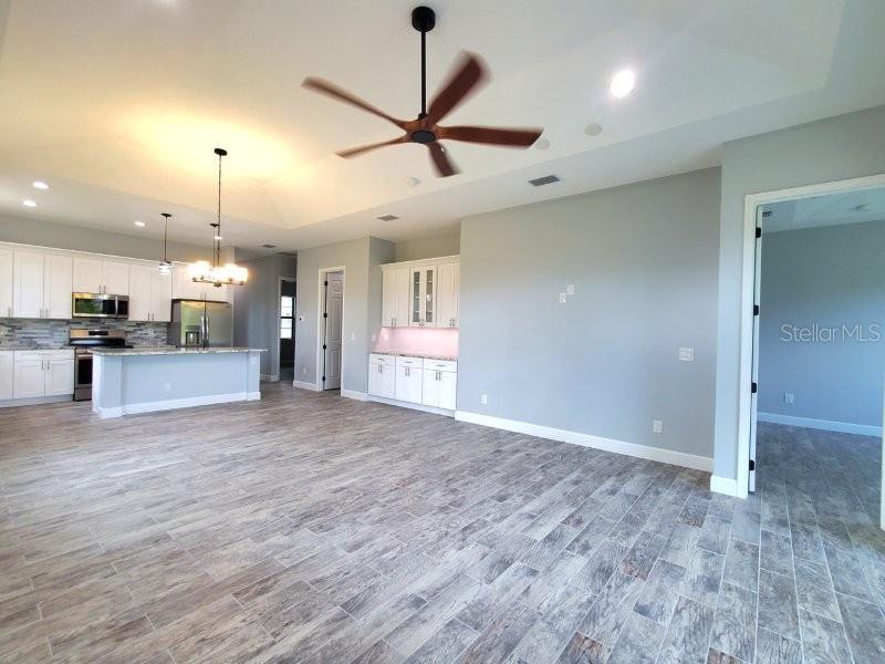 An open-concept kitchen and living area featuring white cabinetry, a ceiling fan, and wood-look flooring — 1038 SAN CRISTOBAL AVENUE, PUNTA GORDA, FL