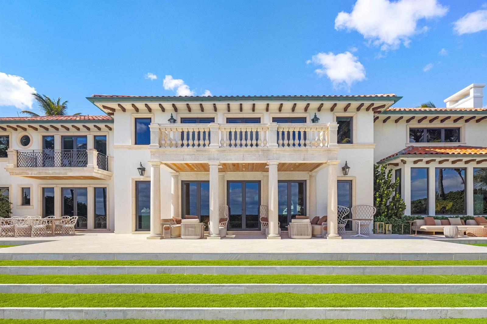 The exterior of a large, two-story Mediterranean-style house with a stone balcony and patio — 680 S Ocean Boulevard, Palm Beach FL 33480, PALM BEACH, FL