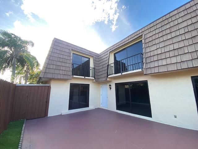 A two-story building exterior features a patio, sliding glass doors, and upper-level balconies — 594 Springdale Circle # d, Palm Springs FL 33461, PALM SPRINGS, FL