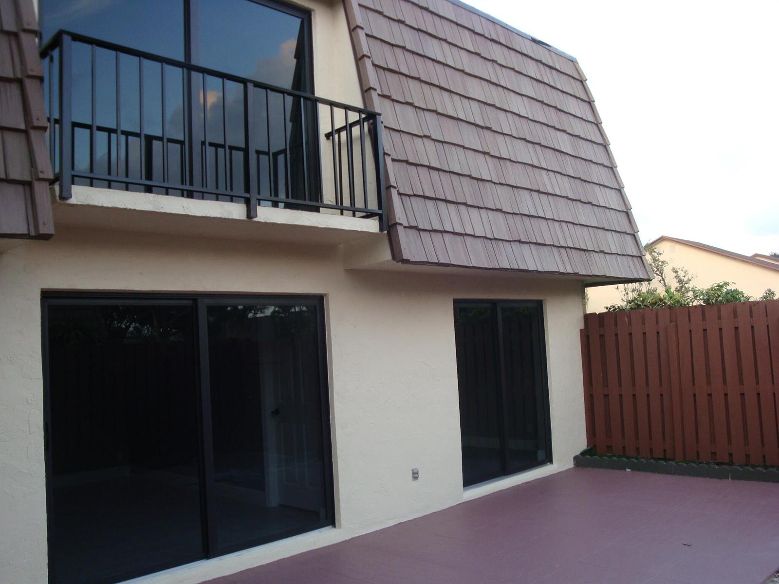 A two-story building exterior with a balcony, sliding glass doors, and a brown tiled roof — 594 Springdale Circle # d, Palm Springs FL 33461, PALM SPRINGS, FL
