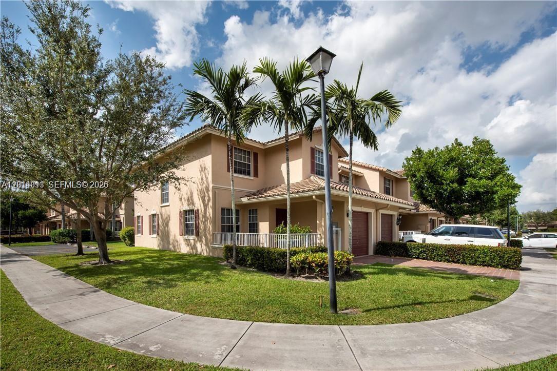 A two-story townhouse with a tan stucco exterior, a tile roof, and a small lawn — 3371 Lakeside Dr # 27, Davie FL 33328, DAVIE, FL
