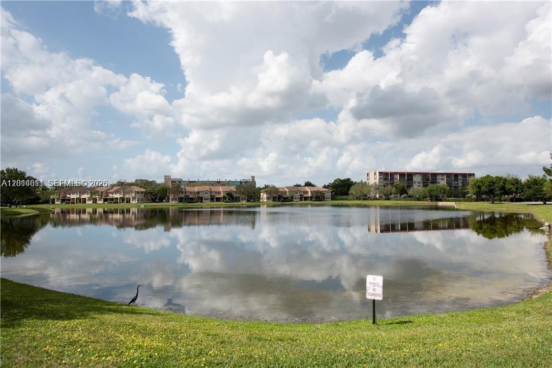 A large pond sits in front of multi-story residential buildings under a cloudy sky — 3371 Lakeside Dr # 27, Davie FL 33328, DAVIE, FL
