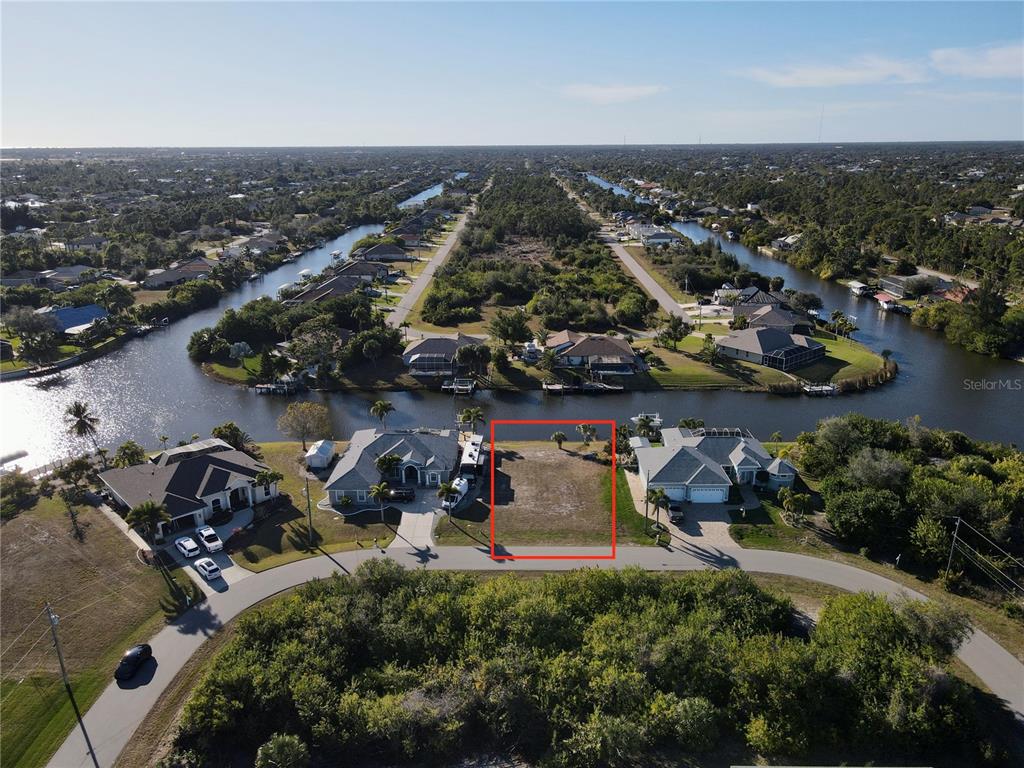 An aerial view shows a vacant waterfront residential lot outlined in red — 15666 APPLEWHITE CIRCLE, PORT CHARLOTTE, FL