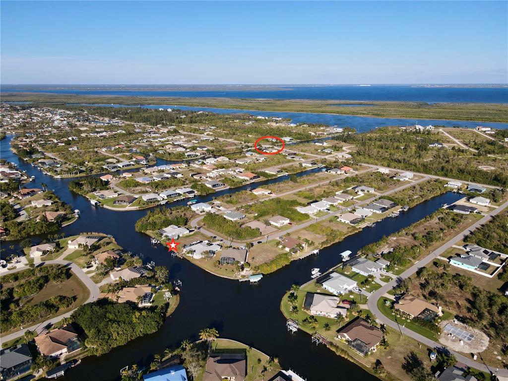 An aerial view shows waterfront houses along canals with a red star and circle overlay — 15666 APPLEWHITE CIRCLE, PORT CHARLOTTE, FL