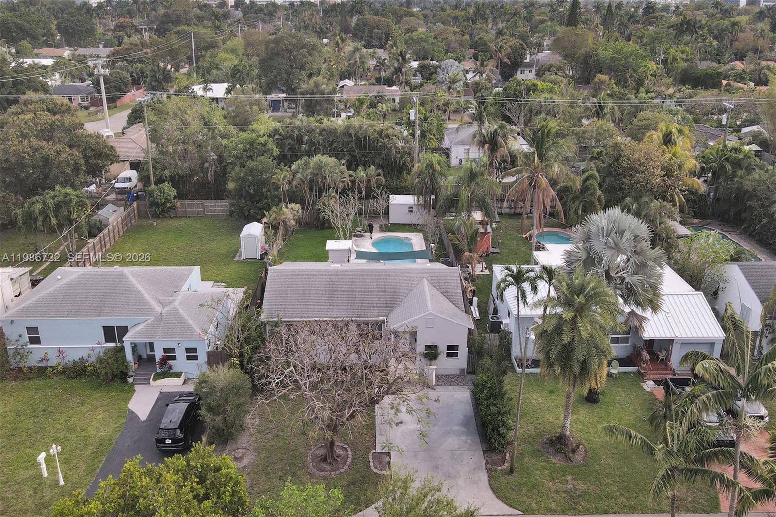 An aerial view shows three adjacent houses with swimming pools and lush tropical landscaping — 1508 Funston St, Hollywood FL 33020, HOLLYWOOD, FL