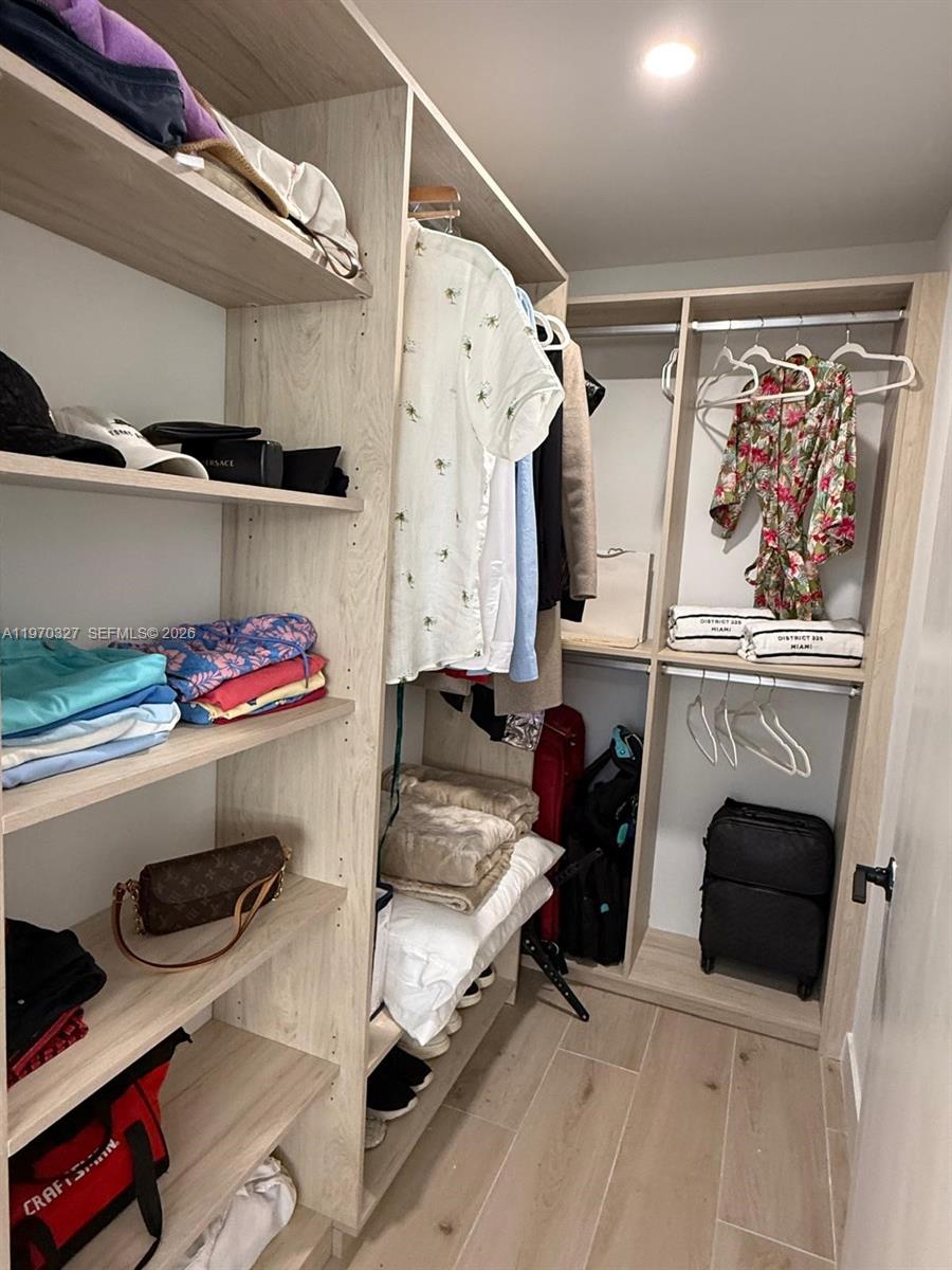 A walk-in closet features light wood shelving, hanging racks, and a tiled floor — 225 N Miami Ave # 804, Miami FL 33128, MIAMI, FL