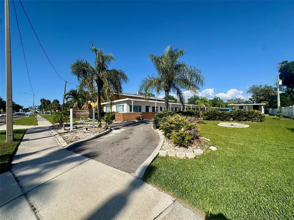 A paved driveway leads to a single-story building with palm trees and a grassy lawn — 2035 EDGEWATER DRIVE UNIT 10, CLEARWATER, FL