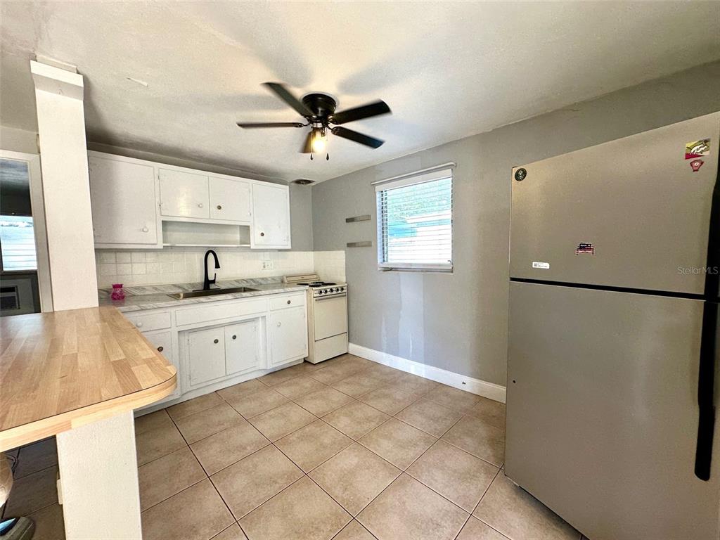 A kitchen features white cabinets, a stainless steel refrigerator, a ceiling fan, and tiled flooring — 2035 EDGEWATER DRIVE UNIT 10, CLEARWATER, FL