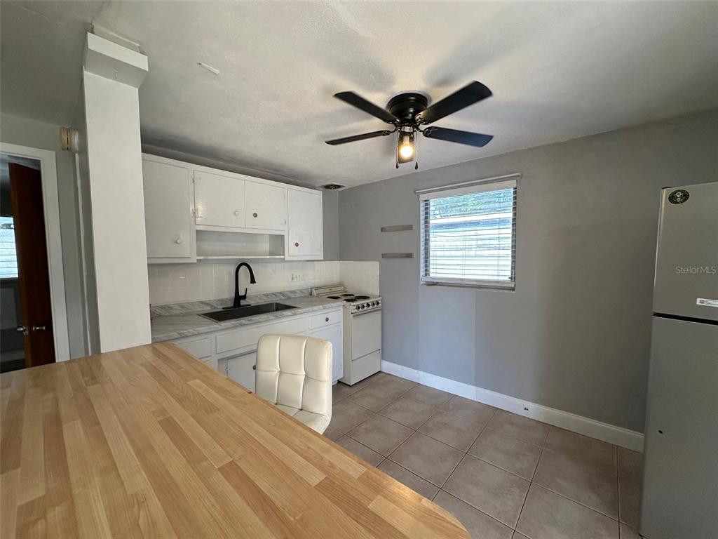 A kitchen features white cabinets, a light wood countertop, a ceiling fan, and tile flooring — 2035 EDGEWATER DRIVE UNIT 10, CLEARWATER, FL
