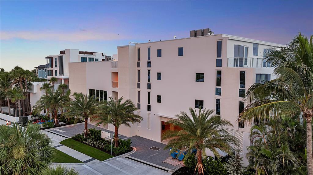 An exterior view of a modern multi-story residential building with palm trees and a driveway — 70 AVENIDA VENECCIA UNIT 304, SARASOTA, FL