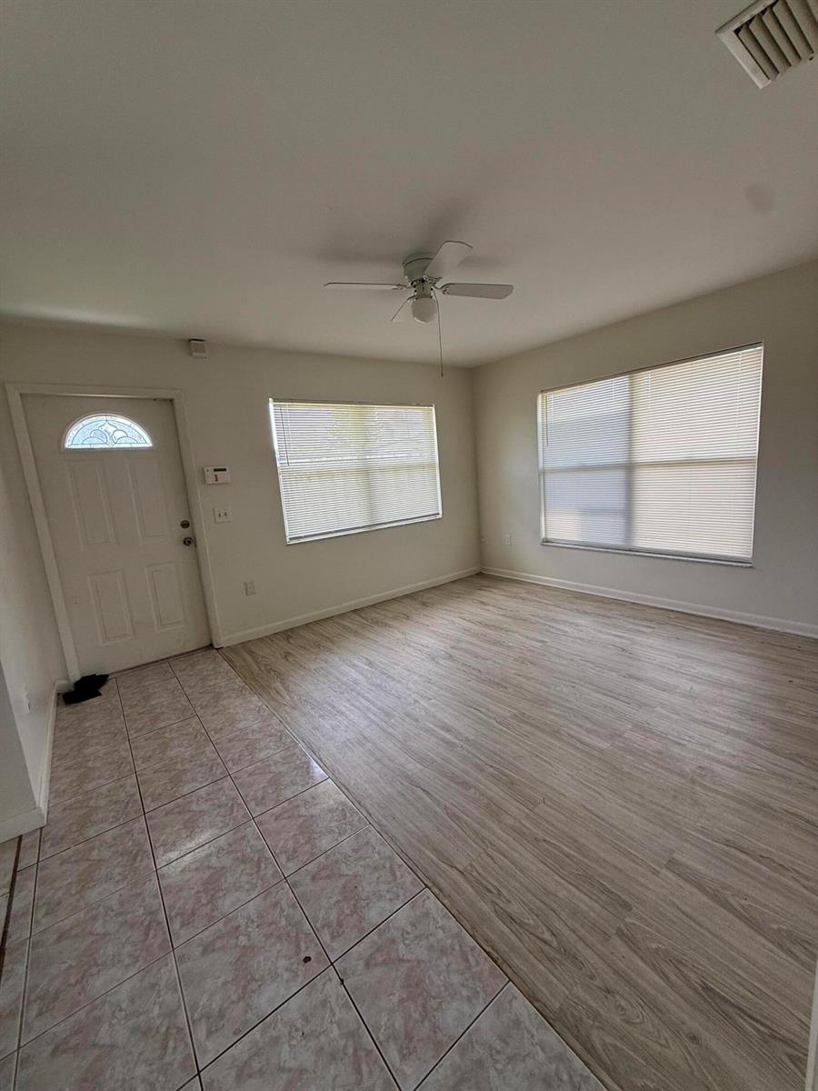 An empty room features light wood-look flooring, a tiled entryway, and a ceiling fan — 3961 Park Lane # B, Palm Springs FL 33406, PALM SPRINGS, FL
