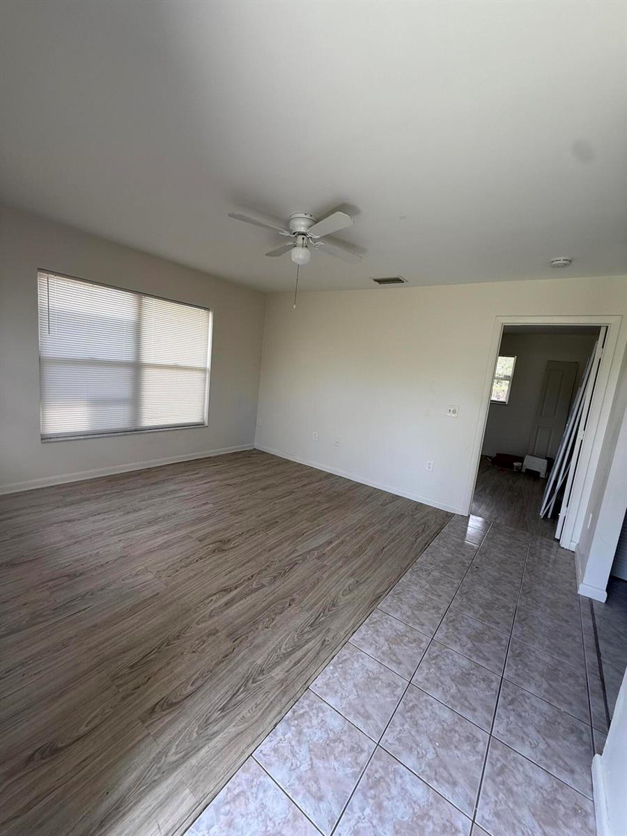 An empty room features light wood-look flooring, a ceiling fan, and a tiled entryway — 3961 Park Lane # B, Palm Springs FL 33406, PALM SPRINGS, FL