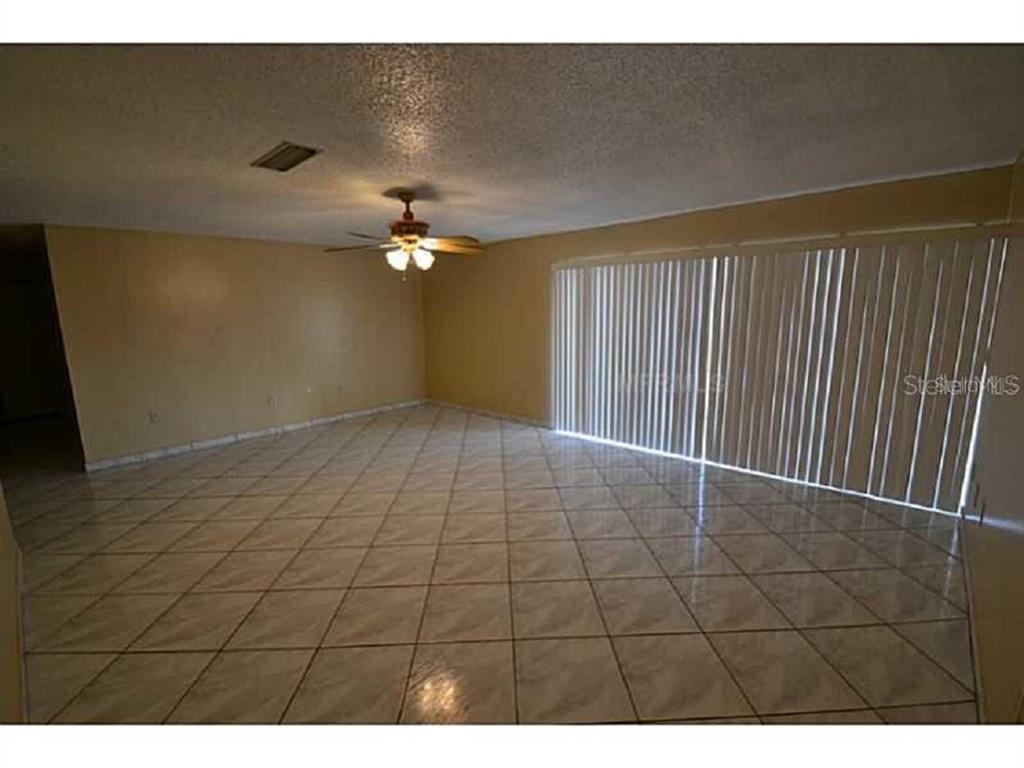 An empty room with beige walls, a ceiling fan, and light-colored tile flooring — 720 100TH AVENUE N UNIT 203, ST PETERSBURG, FL