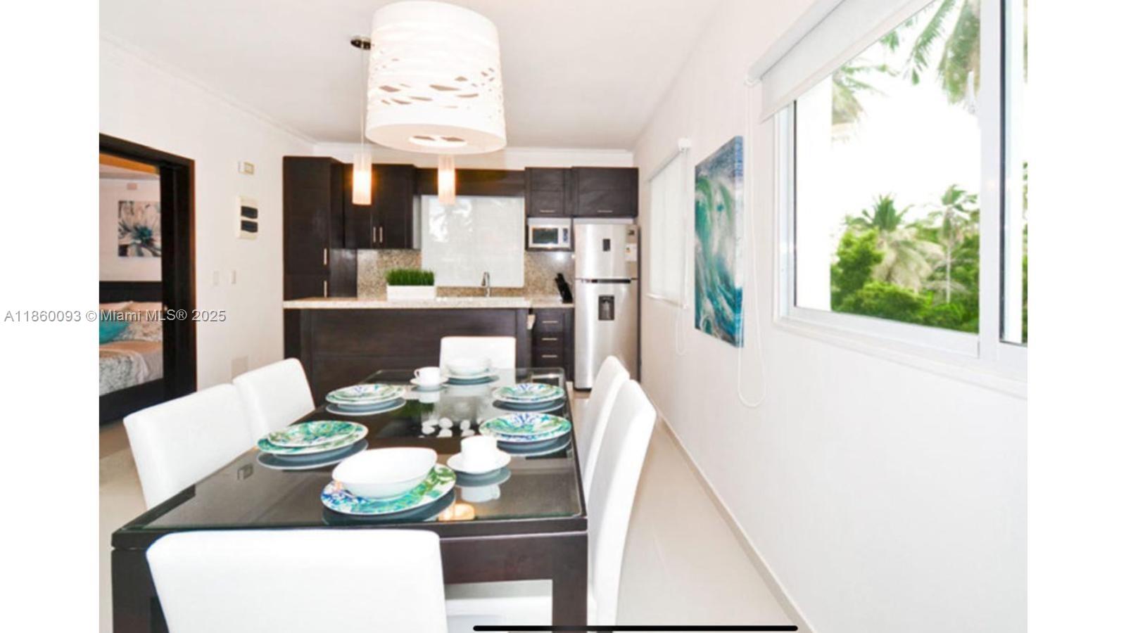 A dining room with a glass-topped table and white chairs sits adjacent to a kitchen — Los Corales Los Corales # 101, La, La
