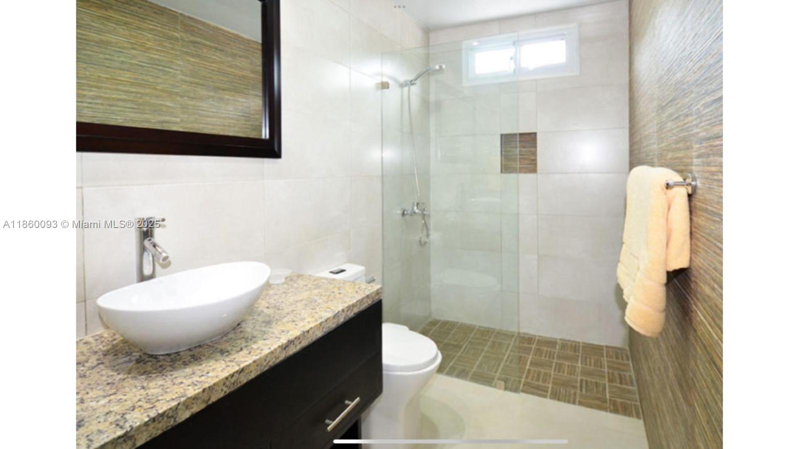 A bathroom features a vessel sink on a granite vanity, a toilet, and a glass-enclosed shower — Los Corales Los Corales # 101, La, La