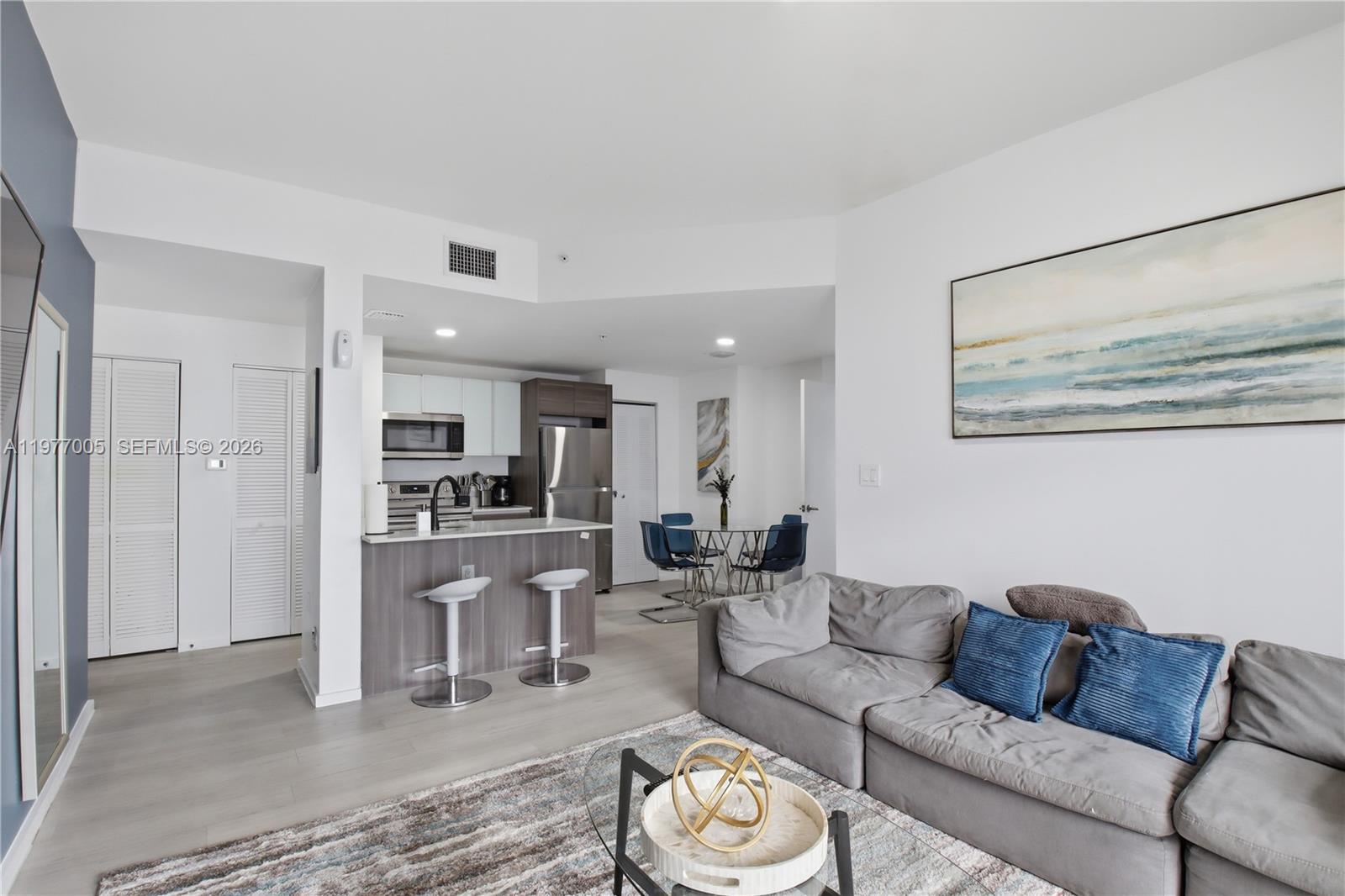 A living room with a grey sofa and a kitchen featuring a breakfast bar — 481 NE 29th St # 604, Miami FL 33137, MIAMI, FL
