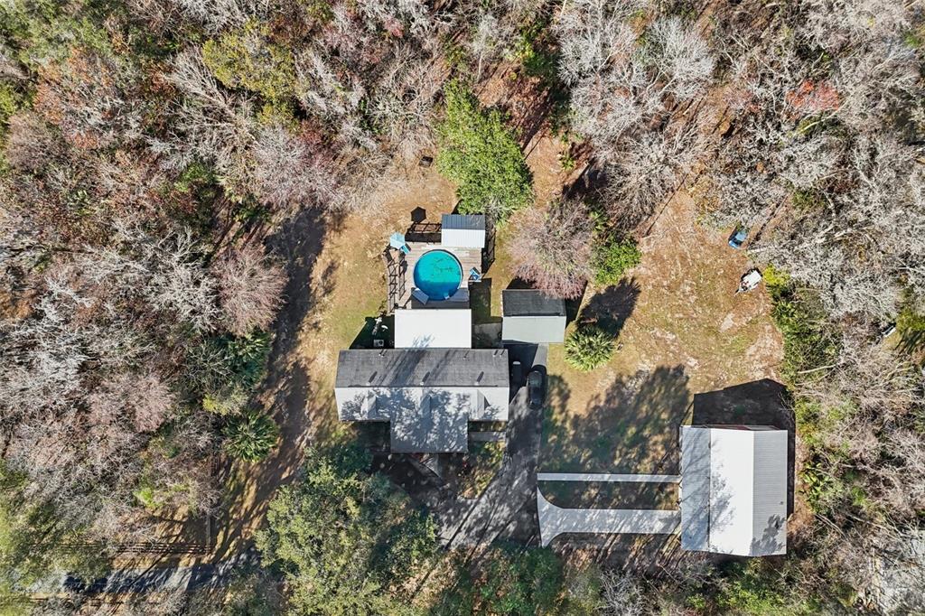 An aerial view shows a house with a circular pool, a detached garage, and surrounding woods — 7459 SW 5TH AVENUE, OCALA, FL