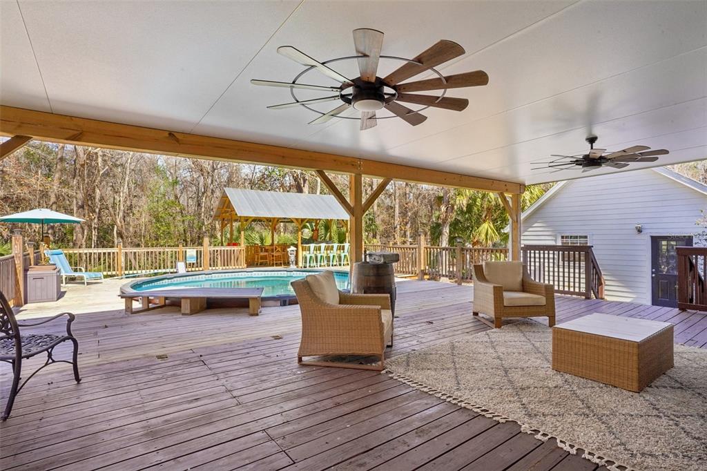 A covered wooden deck features outdoor furniture, ceiling fans, and an above-ground swimming pool — 7459 SW 5TH AVENUE, OCALA, FL