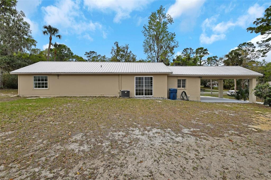 The exterior view shows a single-story house with a metal roof and a carport — 4611 GRAND AVENUE, DE LEON SPRINGS, FL
