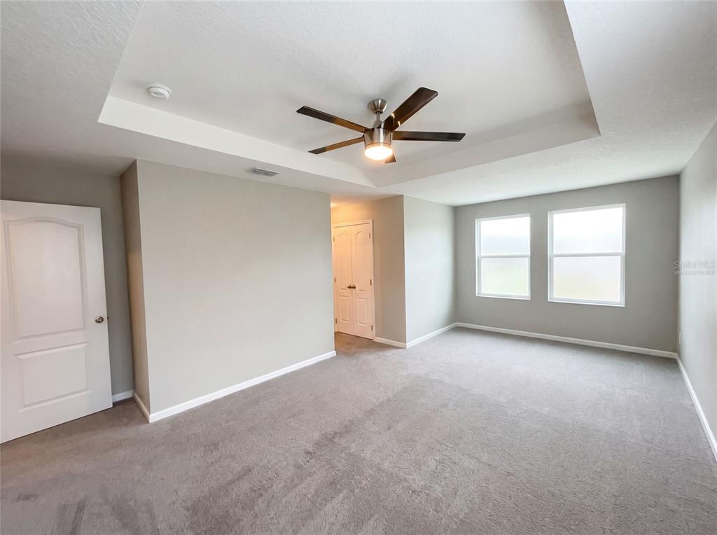 A bedroom with gray carpet, light gray walls, a tray ceiling, and a ceiling fan — 2264 FICUS ALLEY, APOPKA, FL