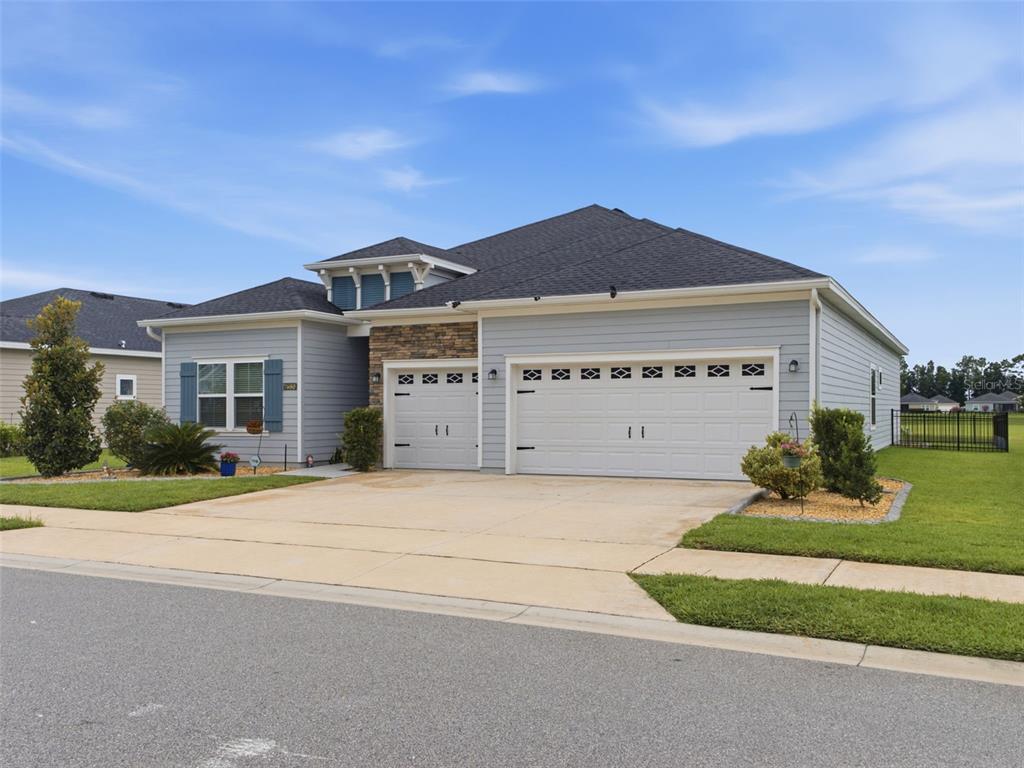 A light blue single-story house with a stone accent, two garage doors, and a driveway — 7680 SW 74TH LOOP, OCALA, FL