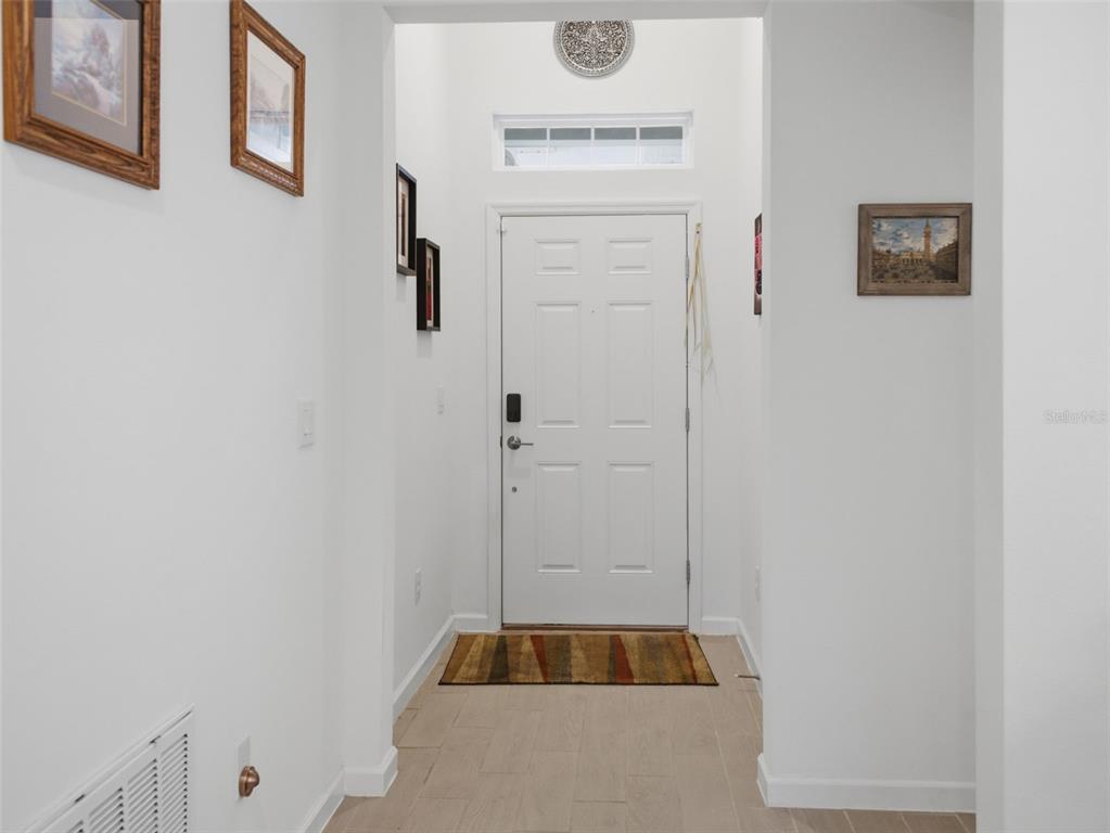 A white front door opens into a bright entryway with light-colored tile flooring — 7680 SW 74TH LOOP, OCALA, FL