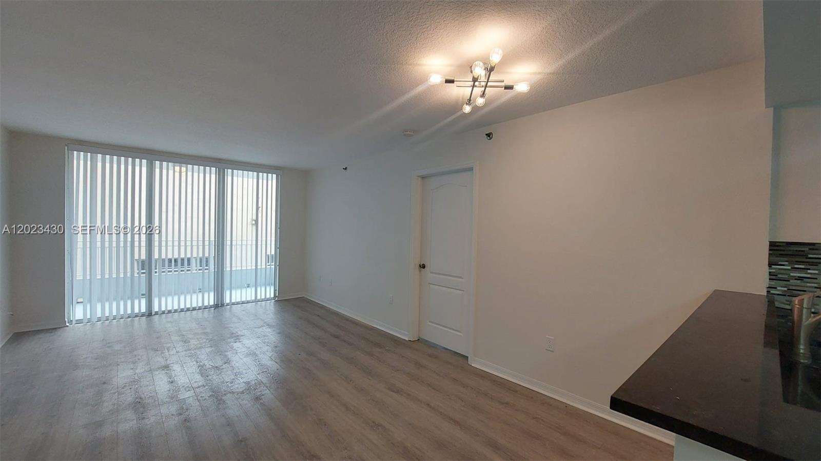 An empty room features light wood-look flooring, a white door, and a modern ceiling light — 2642 Collins Ave # 408, Miami Beach FL 33140, MIAMI BEACH, FL