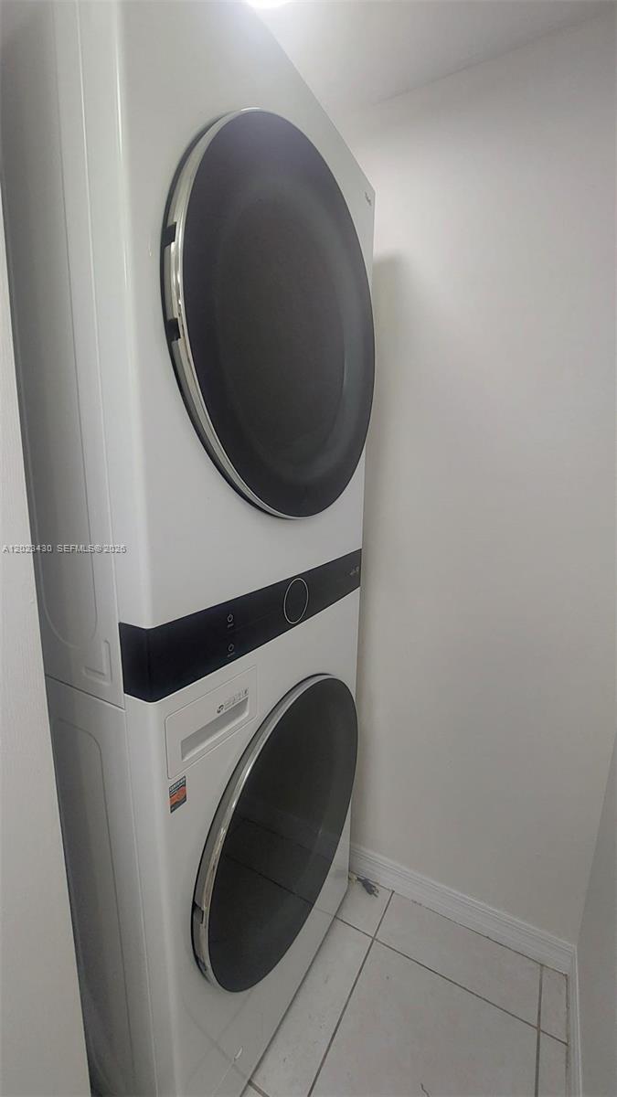 A white stacked washer and dryer unit is installed in a small laundry closet — 2642 Collins Ave # 408, Miami Beach FL 33140, MIAMI BEACH, FL