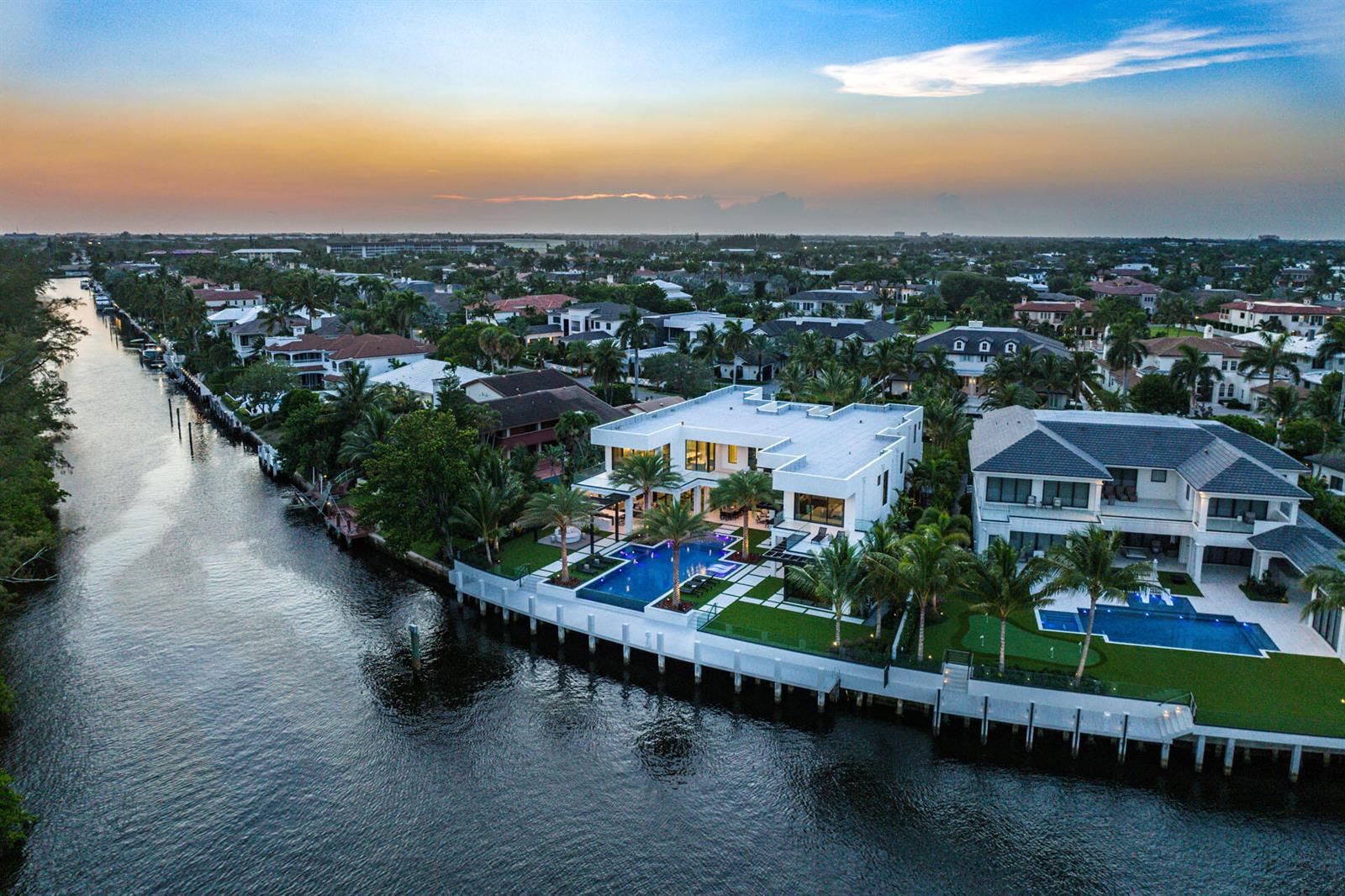 Aerial view of two modern waterfront homes with swimming pools along a canal at sunset — 372 E Alexander Palm Road, Boca Raton FL 33432, BOCA RATON, FL