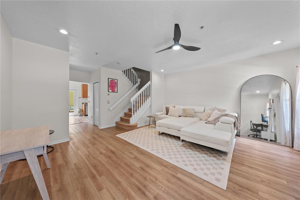 A living room features a white sectional sofa, a large arched mirror, and wooden flooring — 241 DEEPCOVE ROAD, WINTER GARDEN, FL