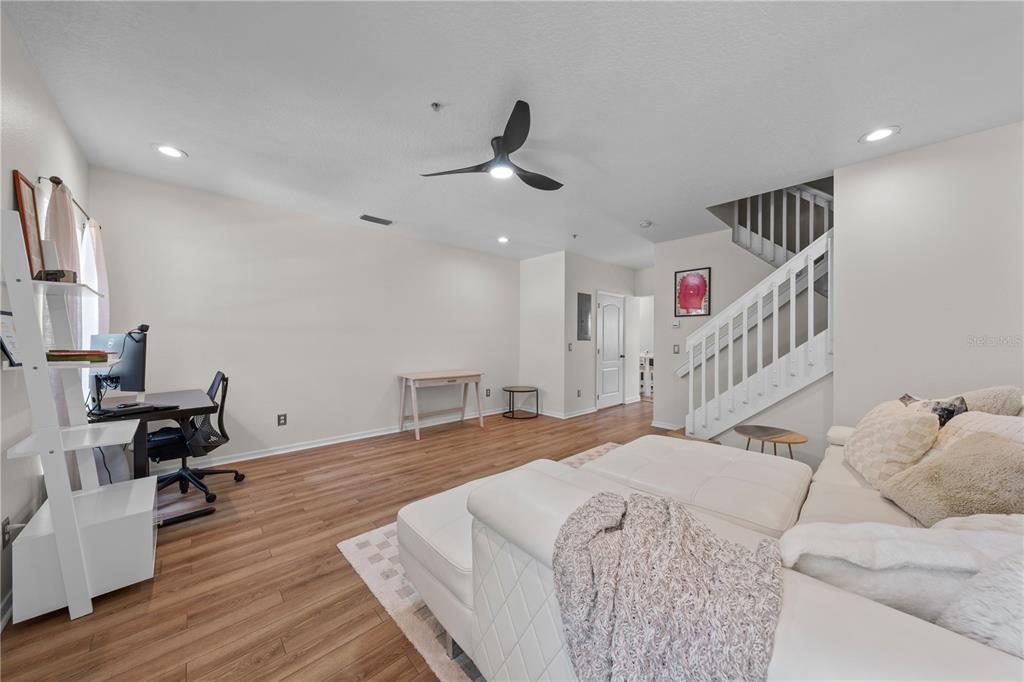 A living room features light wood flooring, a white sectional sofa, and a staircase — 241 DEEPCOVE ROAD, WINTER GARDEN, FL